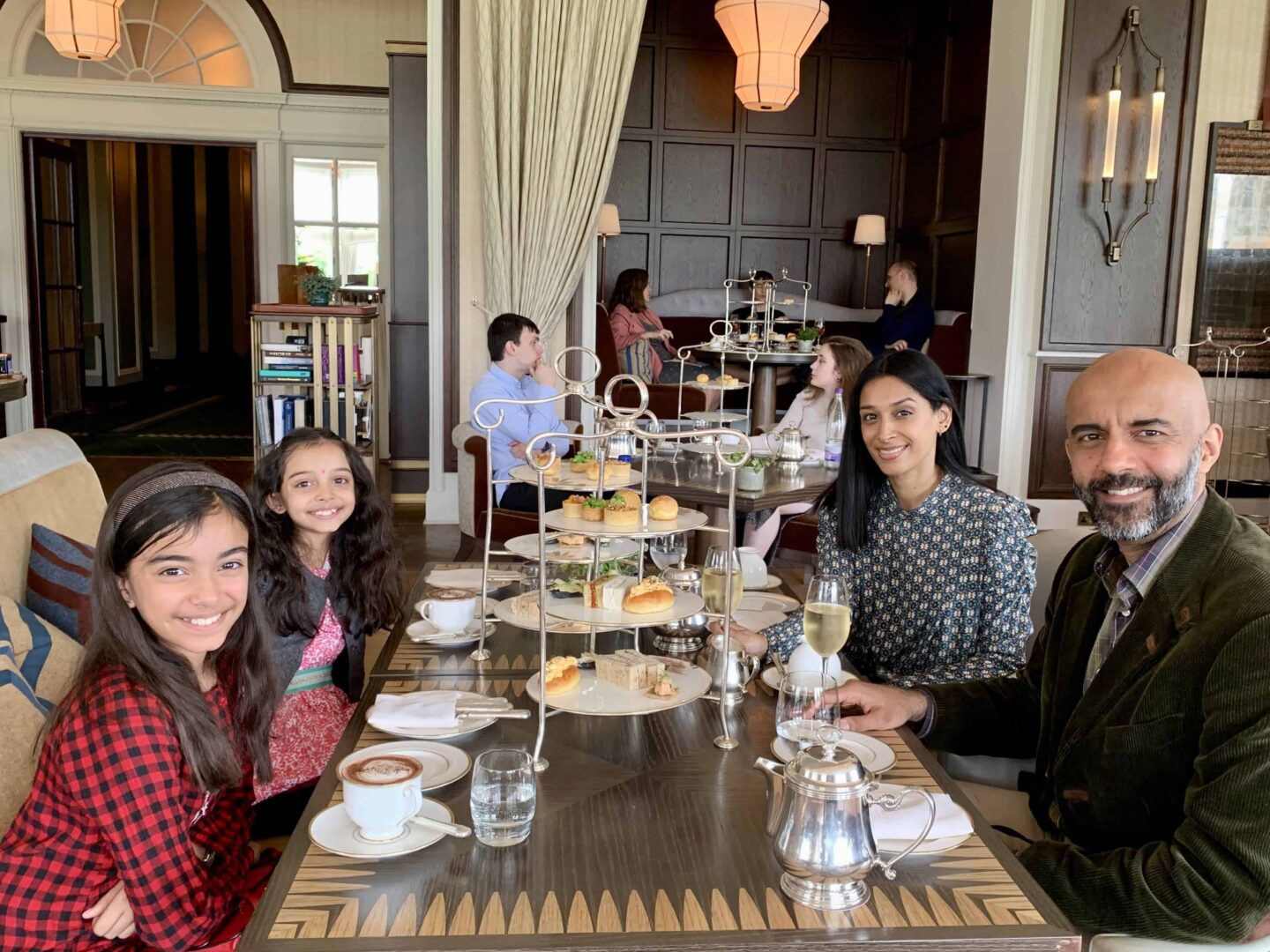 view of the family sat at a table for 4 surrounded by wine, tea, water and afternoon tea