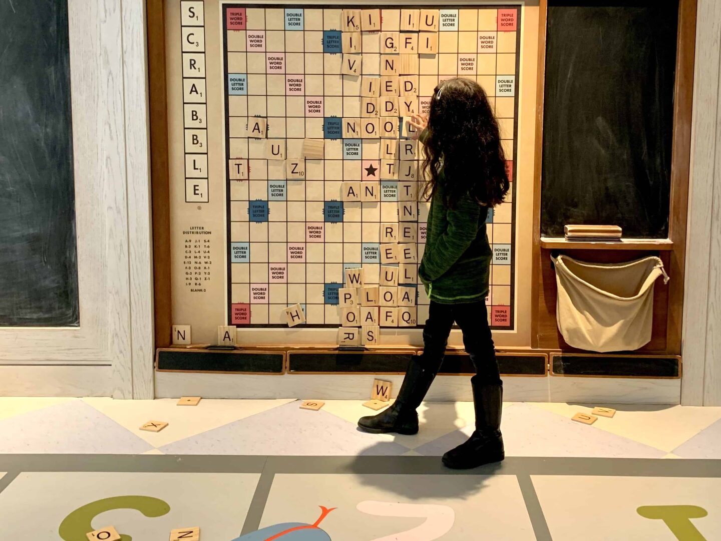 sima daughter playing a large scrabble on the wall in the Den