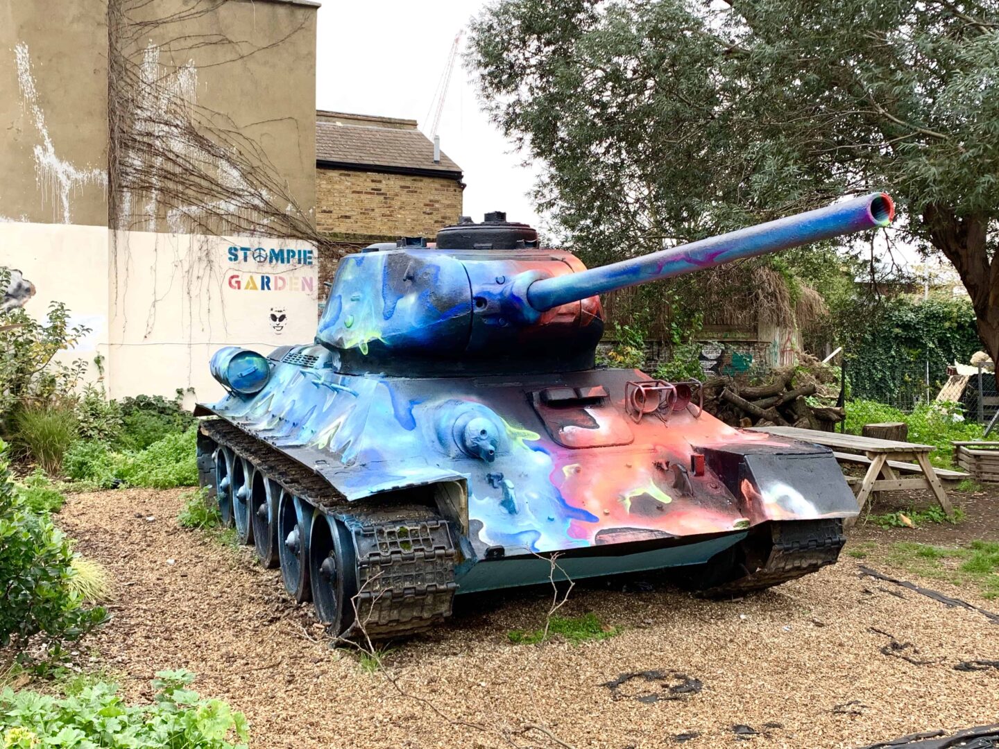 spray painted blue, orange and red T-34 tank on land in London called stompie garden